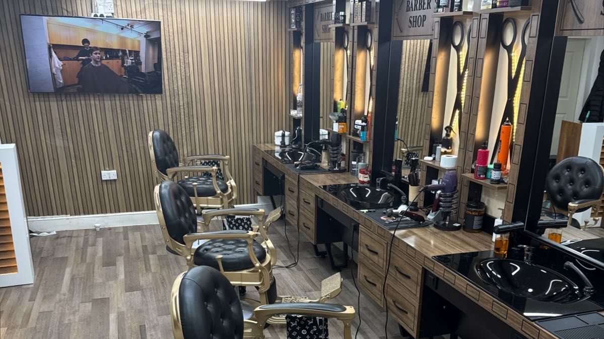 Inside Rayan Barber: gold and black barber chairs facing lit mirrors along a slatted wall