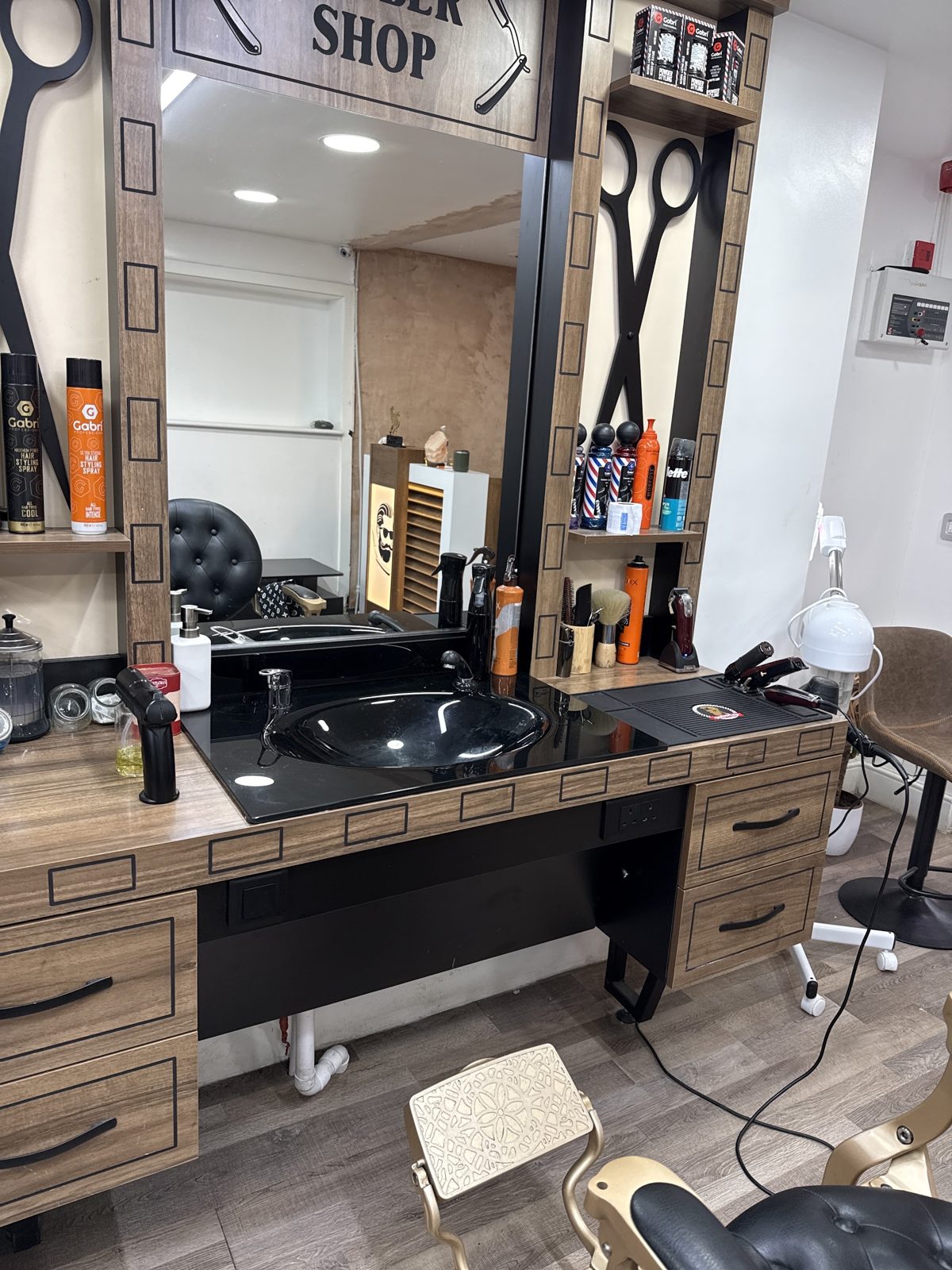 A barber station with basin, mirror and products set out