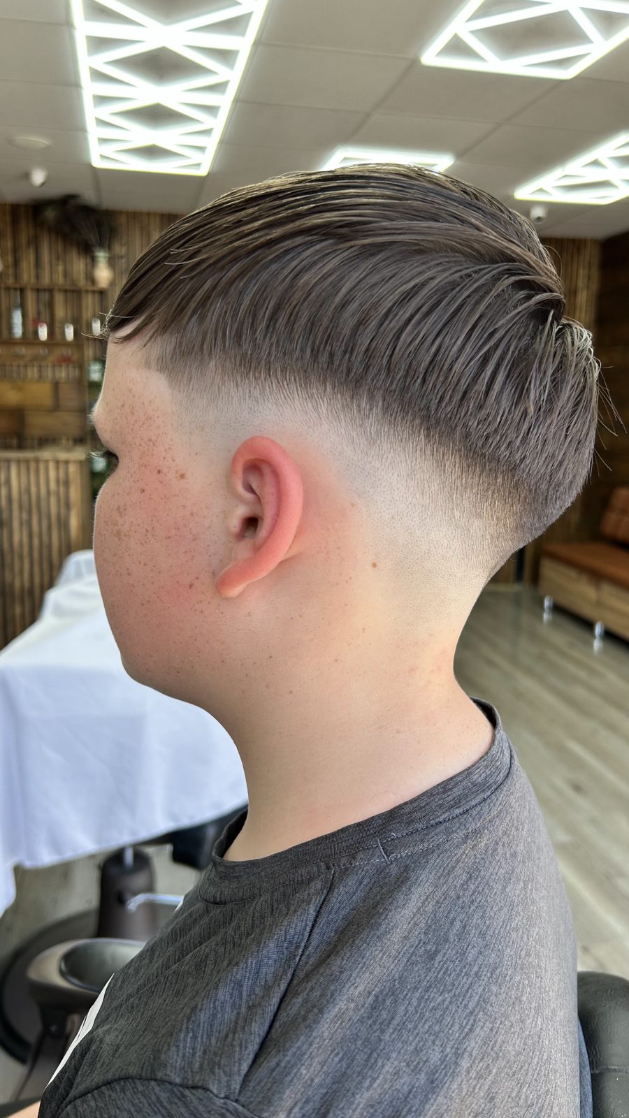 A textured crop with a skin fade, seen from behind under the shop lights